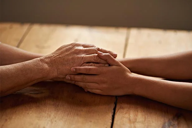 two people holding hands consoling each other